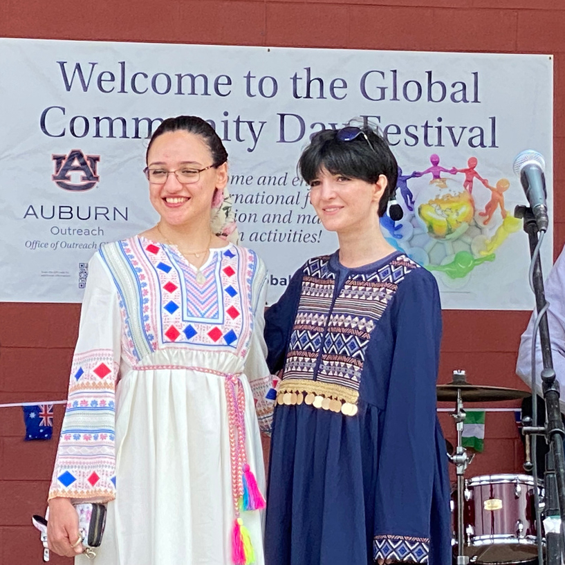 Two women standing on stage wearing cultural attire