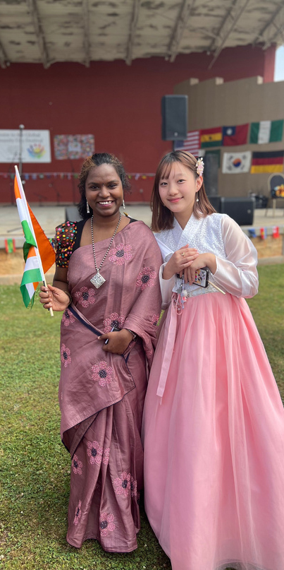 Two females stading in front of the stage wearing cultural attire