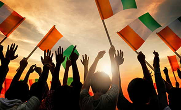 Silhouette of hands with irish flag and sunset in background