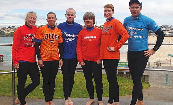 Group photo of people in wet suits after surfing.