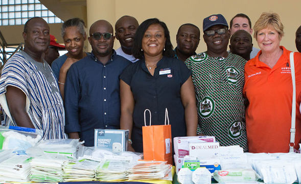 Group of volunteers poses behind table of donated health supplies in Ghana, Africa.