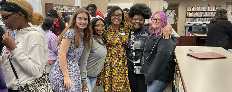 Five women pose for a photo in a library