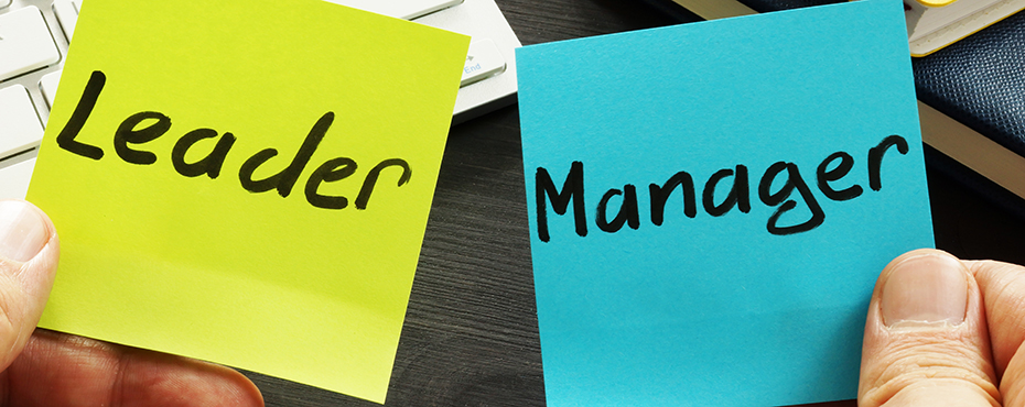 Hands holding two post-its notes, the left is yellow and has 'Leader' written on it, and the right is blue and has 'Manager' written on it.