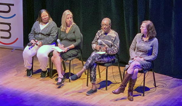 Four women sit on stage during panel discussion about Alabama Prisons