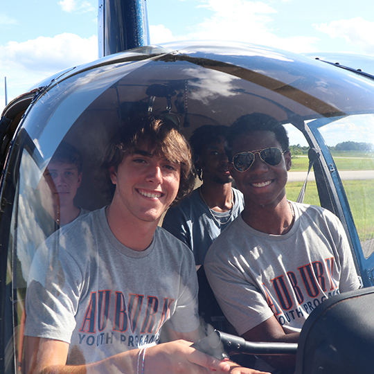 Four male students sitting in a helicopter.