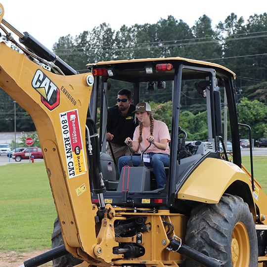 Female student being shown how to work the controls on an excavator