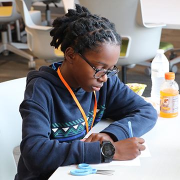 Female student sitting at a desk writing on a piece of paper