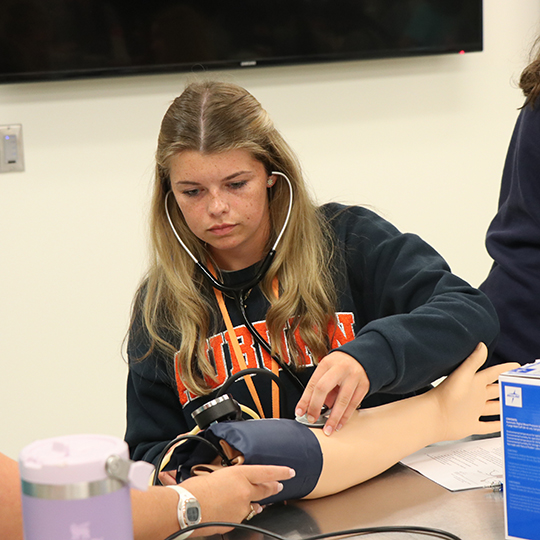 Female student learning how to take blood pressure