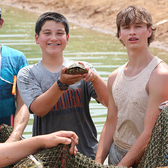 Two male students holding a turtle