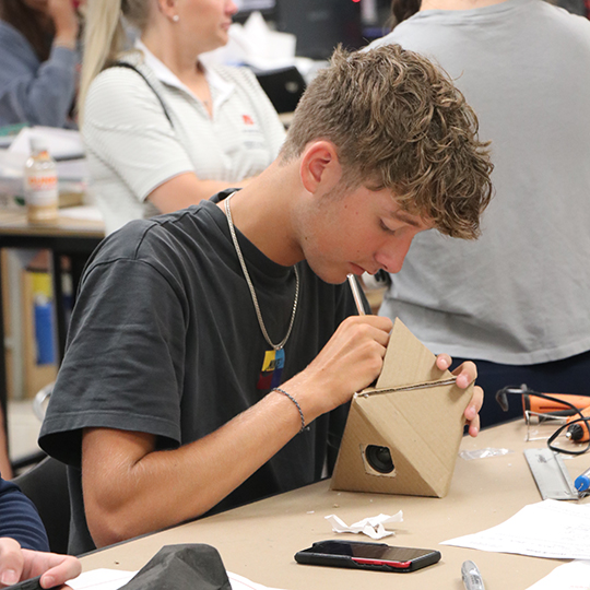 Male student building a cardboard model