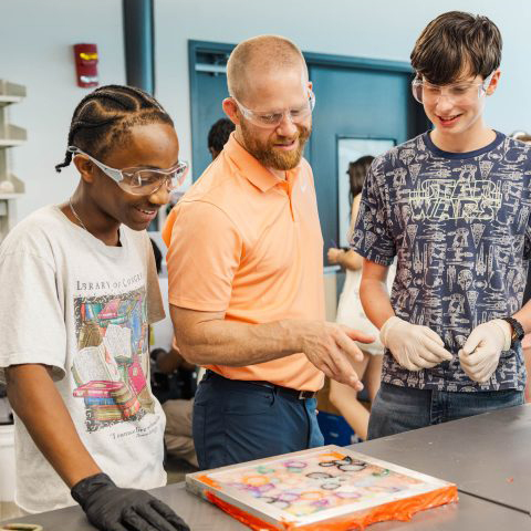 An instructor and two students look at a design project