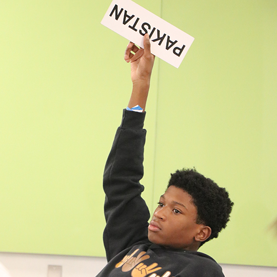 Male student holding sign with word Pakistan