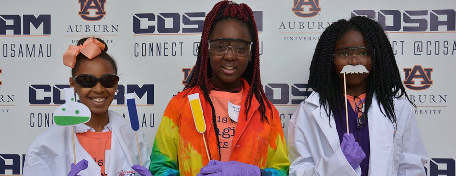 Three female students in front of a COSAM background