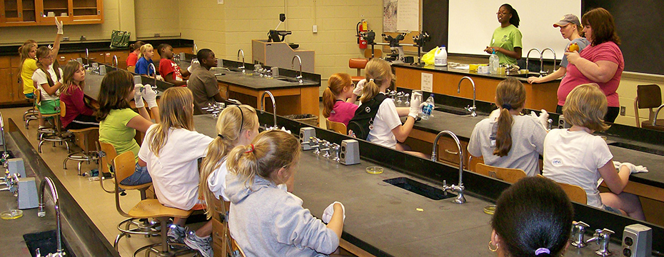 Three instructors teaching students sitting in a chemistry lab classroom