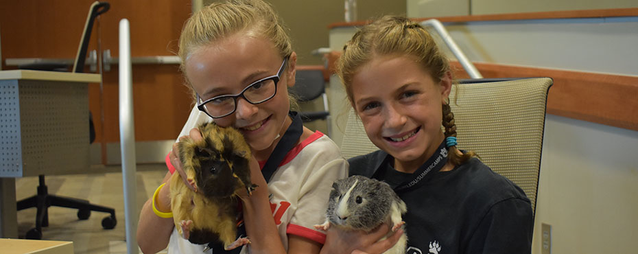Two students hold exotic animals from the Veterinary School.