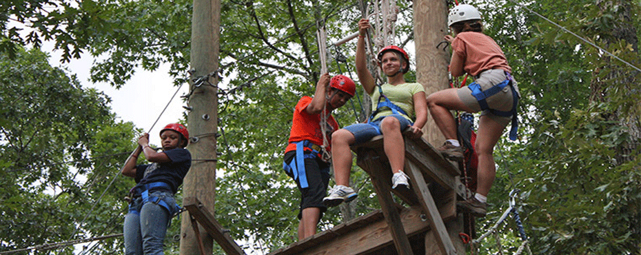 Participants at the challenge course prepare to use the zipline.