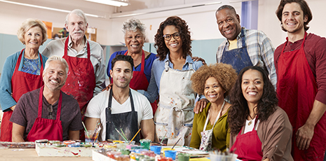 Group photo of people wearing red aprons during painting class