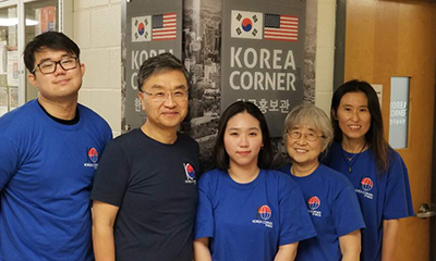 Five people pose for photo in front of Korea Corner sign