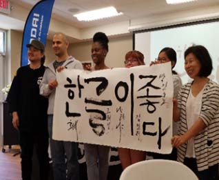 Group of people hold up large banner with Korean language symbols painted on it.