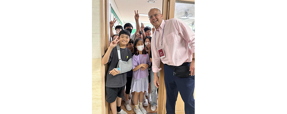 Group of school aged children smiling at camera with one adult male program participant.