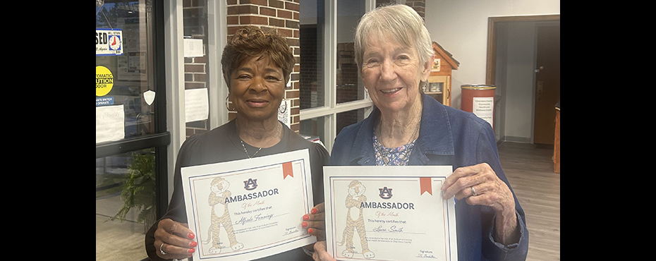 Two Auburn University Rural Health Ambassadors proudly holding their certificates as they are recognized as Ambassadors of the Month, standing side by side with smiles.