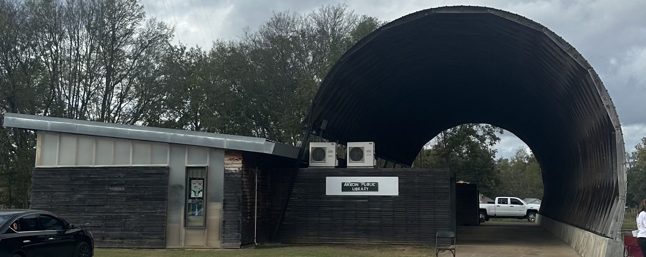 Front view of the Akron Public Library in Hale County, Alabama, a brick building with a small parking area and clear signage near the entrance. 