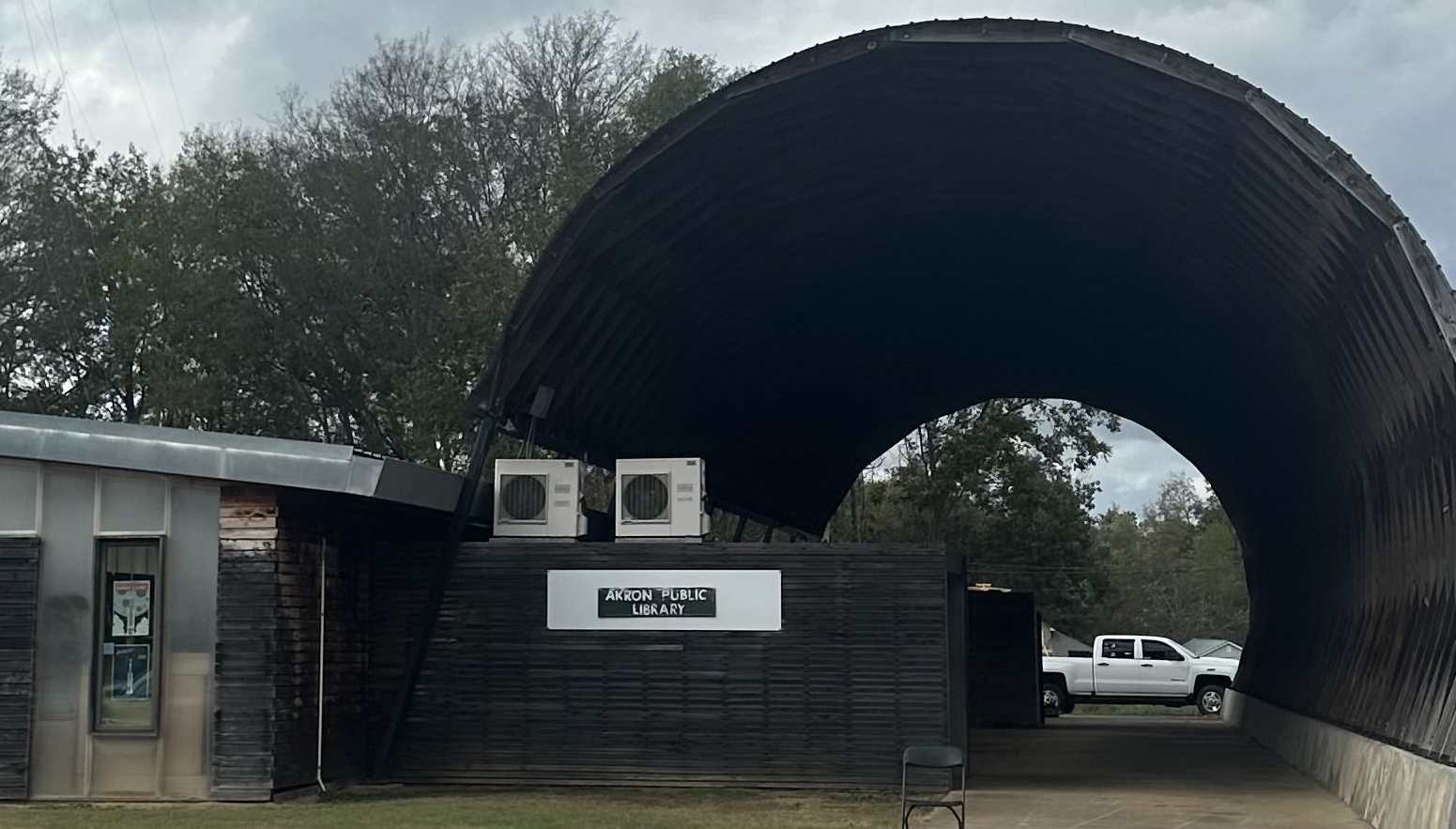 Front view of the Akron Public Library in Hale County, Alabama, a brick building with a small parking area and clear signage near the entrance. 