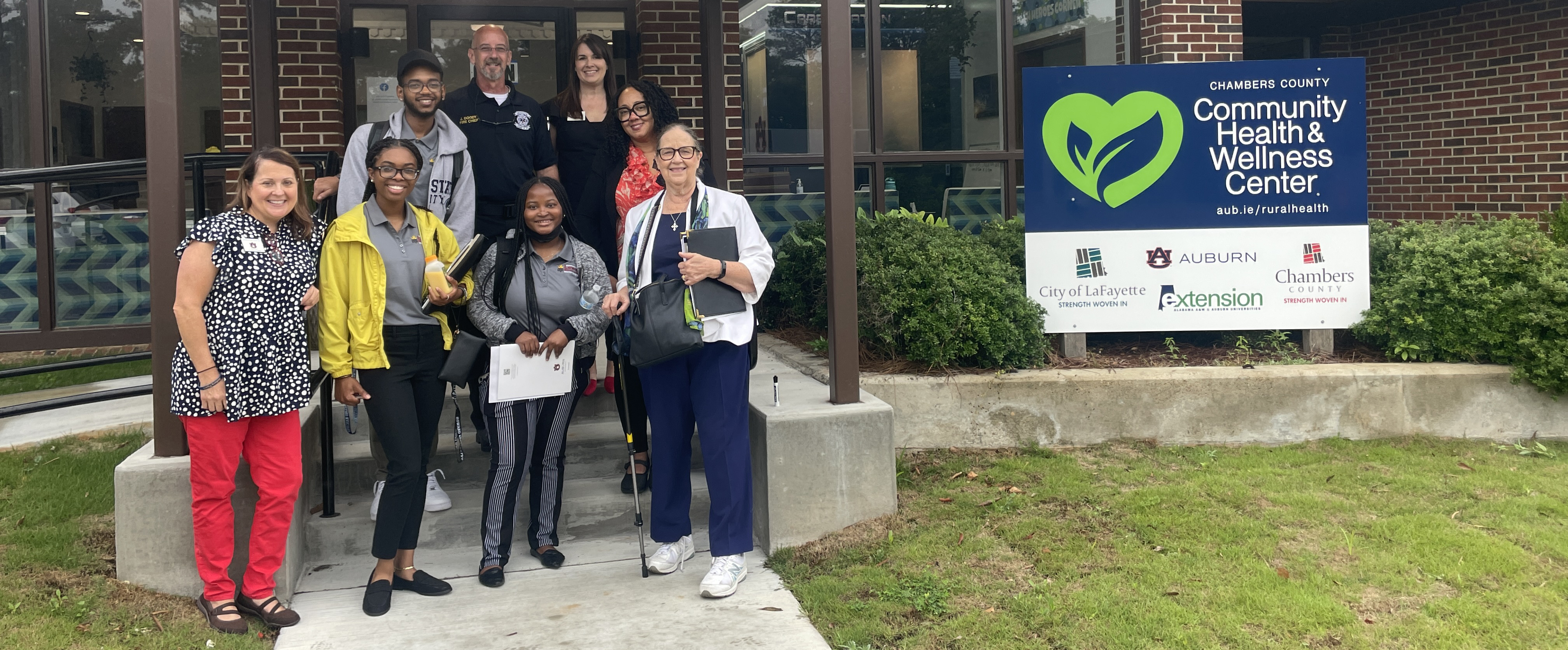 RHI team members Gibson-Young and Snoddy with community group in front of Center